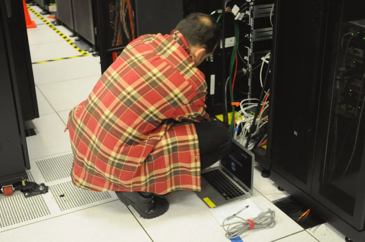 A technician working on rack-mounted equipment in a server room, where IPTV encoders are often installed