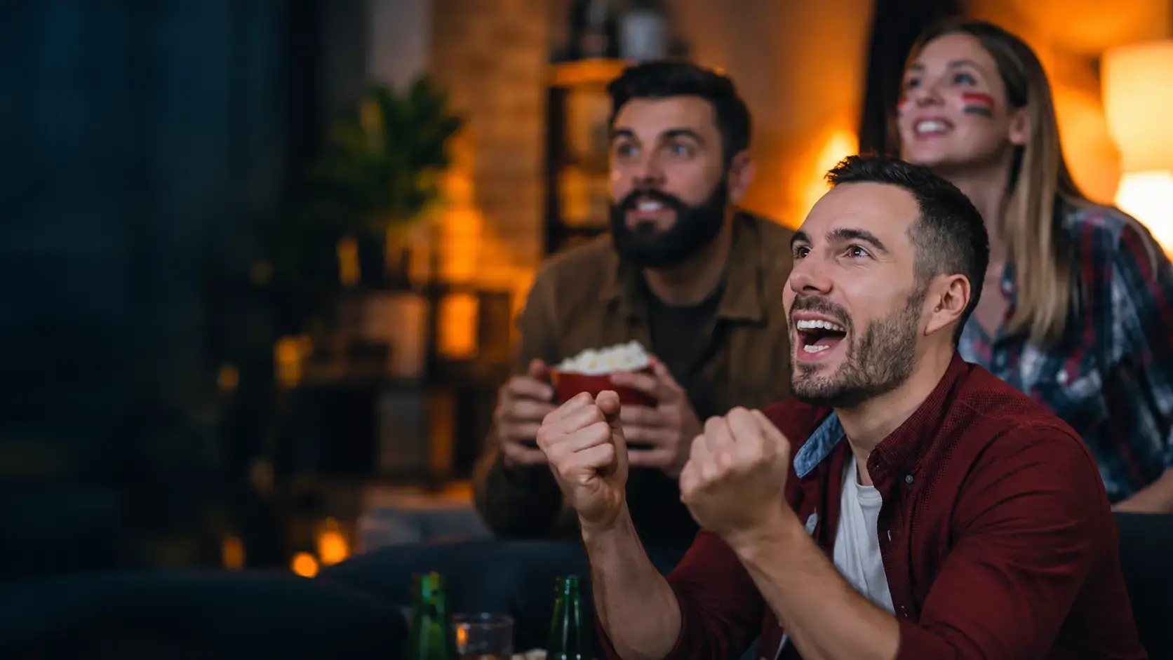 Friends cheering while watching a live match on TV at home